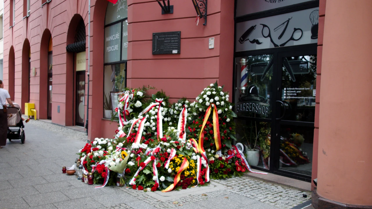 Budynek z tablicą poświęconą Antoniemu Chruścielowi. Poniżej tablicy, na ulicy złożono wiele kwiatów i wieńców.