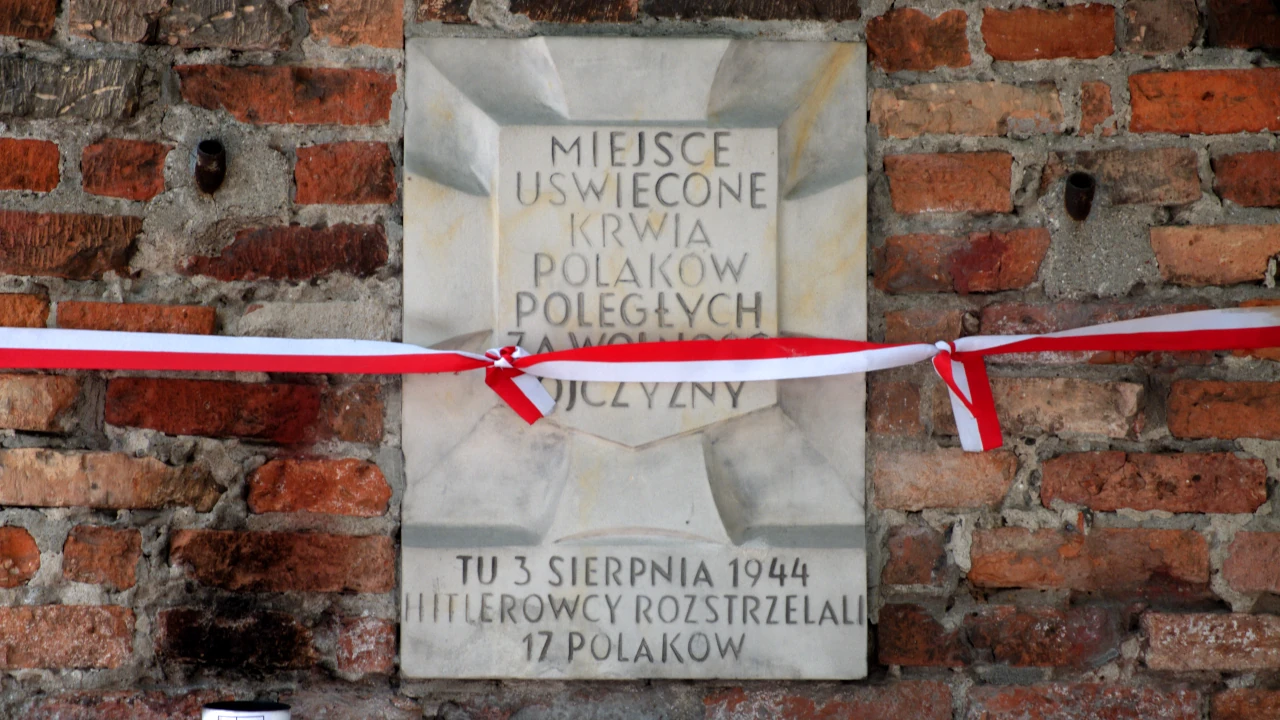 Zbliżenie tablicy z napisem: Miejsce uświęcone krwią Polaków poległych za wolność ojczyzny. Tu 3 sierpnia 1944 roku hitlerowcy rozstrzelali 17 Polaków.