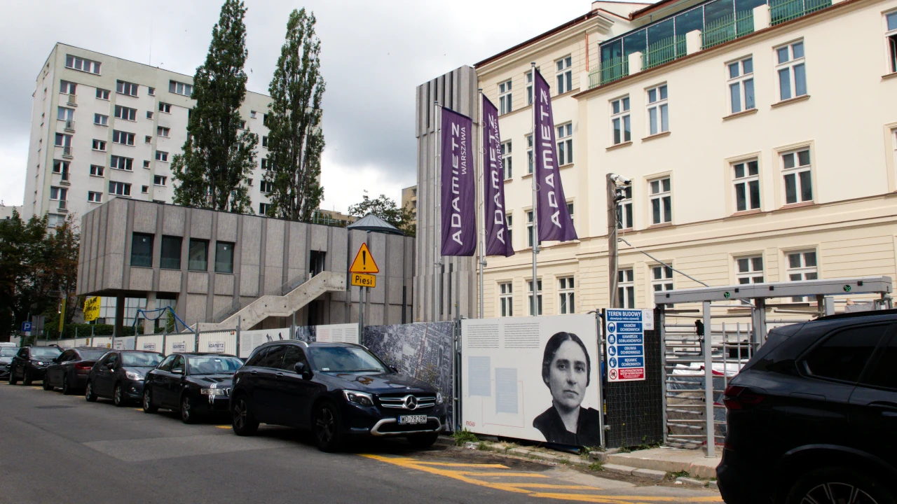 Płot budowy Muzeum Getta Warszawskiego. W tle odnowiona przedwojenna kamienica i dobudowany współczesny betonowy budynek – siedziba muzeum.