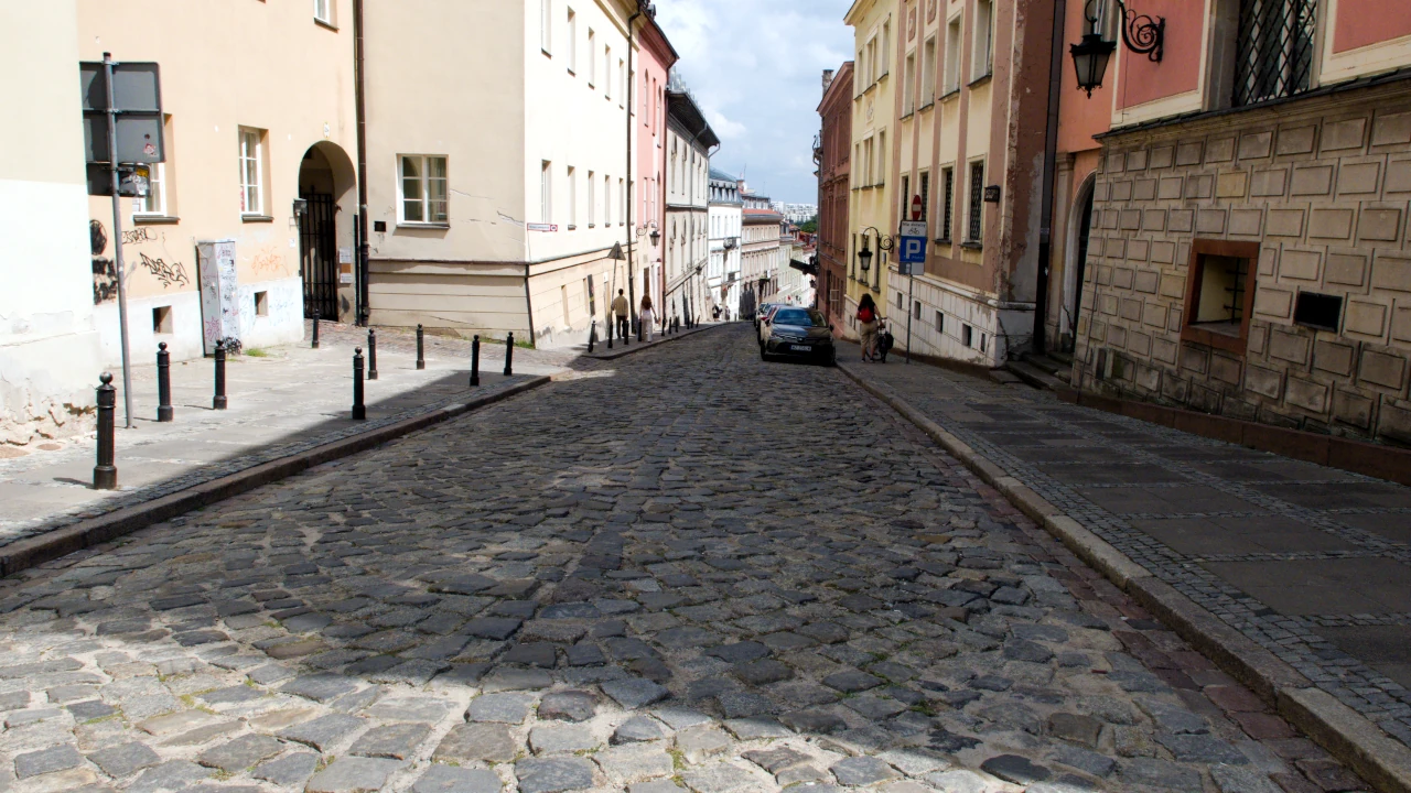 Widok brukowanej ulicy biegnącej w dół.