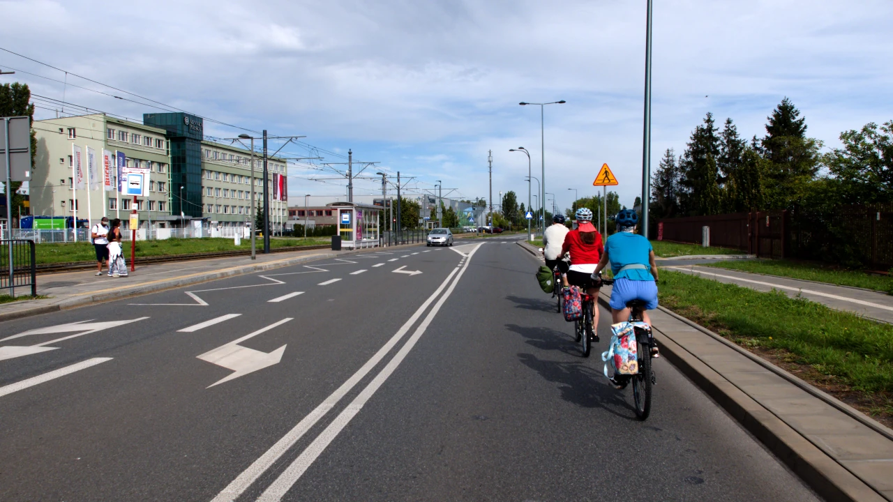 Troje rowerzystów przemieszczających się ulicą, ujęcie z tyłu.