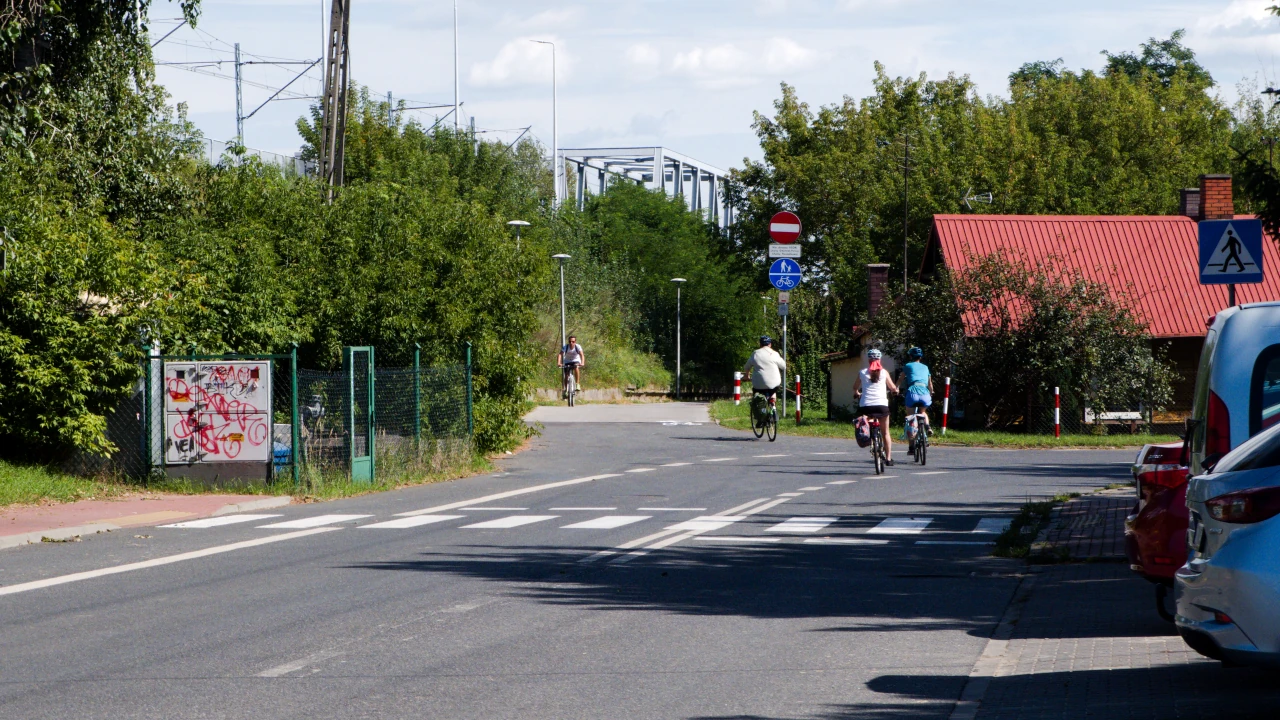 Po ulicy przemieszcza się kilka osób na rowerach.